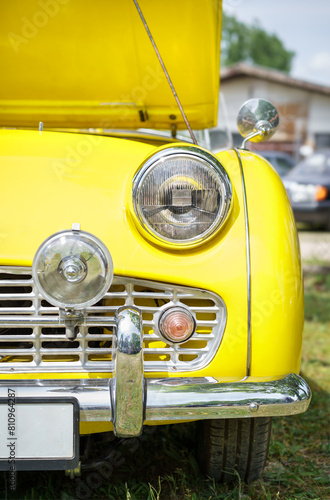 Front view of a yellow vintage car headlights. Classic car. Open hood. 