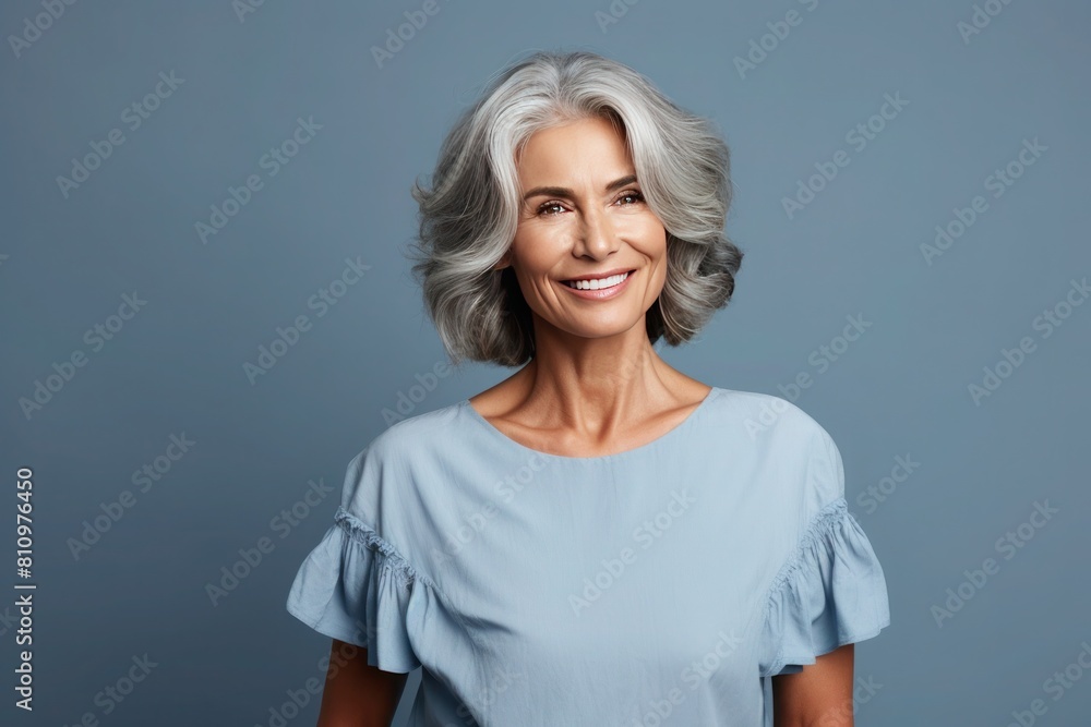 Portrait of beautiful happy 55s old tanned woman with long bob haircut in light blue blouse on blue background Portrait of beautiful happy 55s old tanned woman with long bob haircut in light blue blouse on blue background