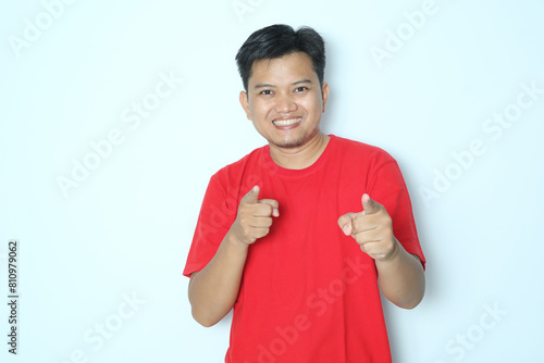 Young Asian man smiling happy while pointing to the camera. Wearing red a shirt photo