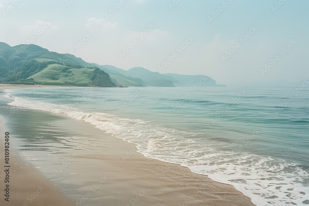 Peaceful beach scene with gentle waves washing over sandy shores, backed by lush green hills under a soft, hazy sky. Peaceful beach scene with gentle waves washing over sandy shores, backed by lush green hills under a soft, hazy sky.