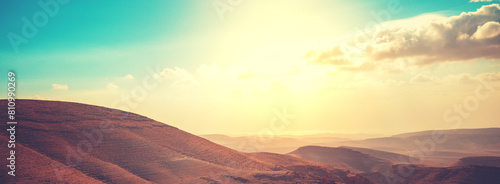 Mountainous desert with colorful cloudy sky. Judean desert in Israel at sunset. Horizontal banner