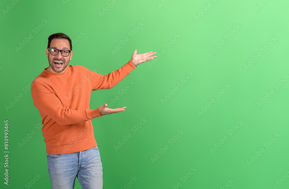 Joyful young businessman advertising new product with hands on copy space over green background Joyful young businessman advertising new product with hands on copy space over green background