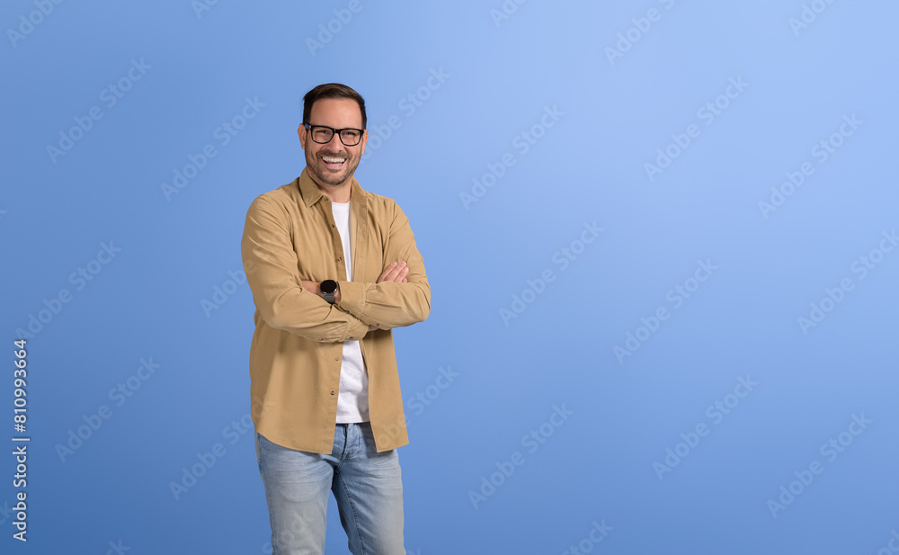 Portrait of confident male manager in glasses with arms crossed posing cheerfully on blue background Portrait of confident male manager in glasses with arms crossed posing cheerfully on blue background