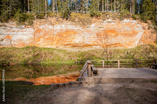 scenic view of a red sandstone cliff from a wooden viewing platform by the river photo