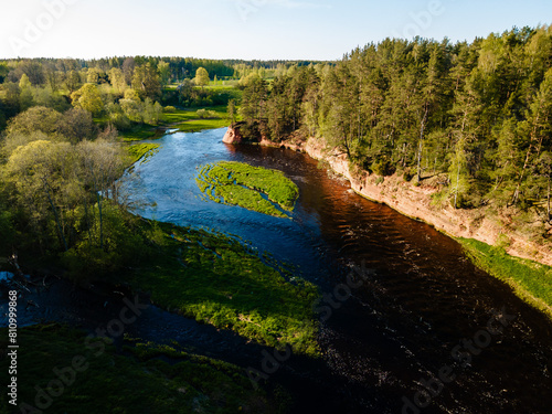 breathtaking aerial view of a river meandering through lush green landscapes with red cliff banks