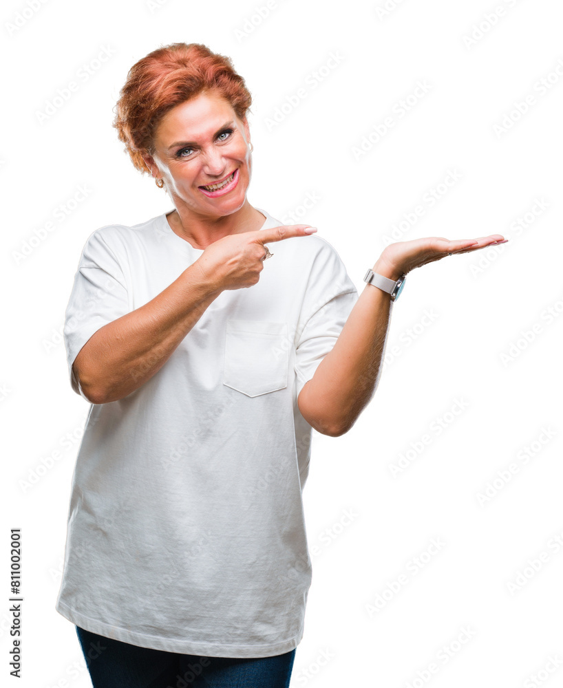 Atrractive senior caucasian redhead woman over isolated background amazed and smiling to the camera while presenting with hand and pointing with finger. Atrractive senior caucasian redhead woman over isolated background amazed and smiling to the camera while presenting with hand and pointing with finger.
