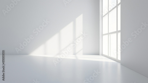 Minimalist empty room with sunlight streaming through large windows  casting soft shadows on white walls and floor.