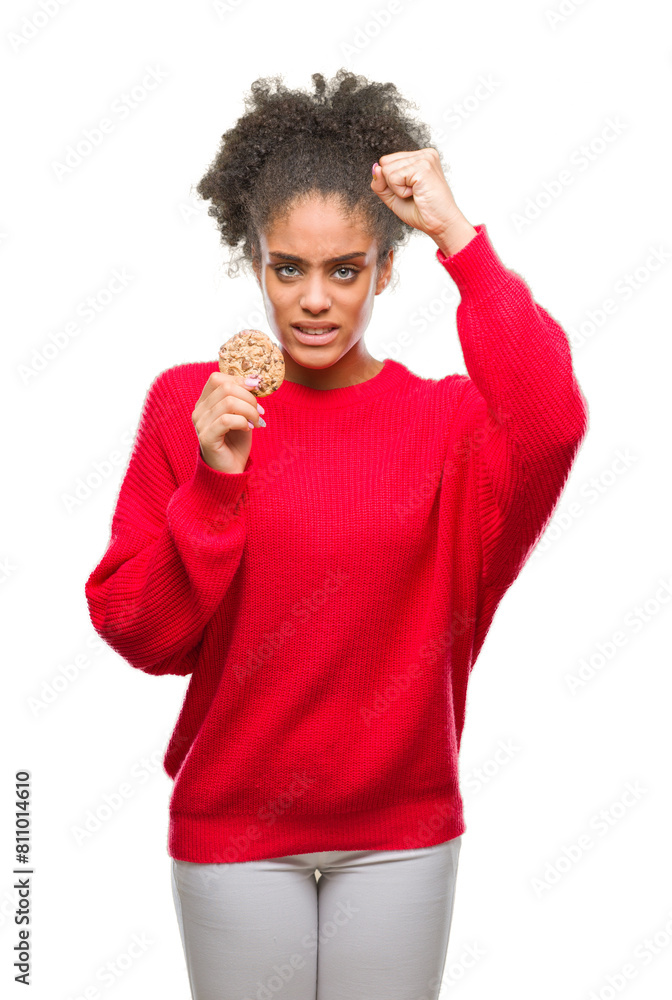 Young afro american woman eating chocolate cookie over isolated background annoyed and frustrated shouting with anger, crazy and yelling with raised hand, anger concept Young afro american woman eating chocolate cookie over isolated background annoyed and frustrated shouting with anger, crazy and yelling with raised hand, anger concept