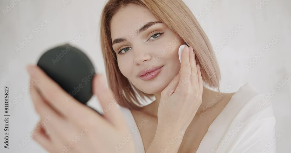 Young brunette woman look in the small round mirror and removing makeup from her face with cotton pad. Skin care. Body care. Skincare and cleaning procedure at home. Love yourself. Young brunette woman look in the small round mirror and removing makeup from her face with cotton pad. Skin care. Body care. Skincare and cleaning procedure at home. Love yourself.