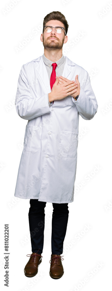 Young handsome scientist man wearing glasses smiling with hands on chest with closed eyes and grateful gesture on face. Health concept. Young handsome scientist man wearing glasses smiling with hands on chest with closed eyes and grateful gesture on face. Health concept.