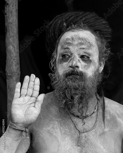 Portrait of an holy male naga sadhu baba with ash on his and long hairs wearing rudraksha necklace during the kumbh festival in India.	
 photo