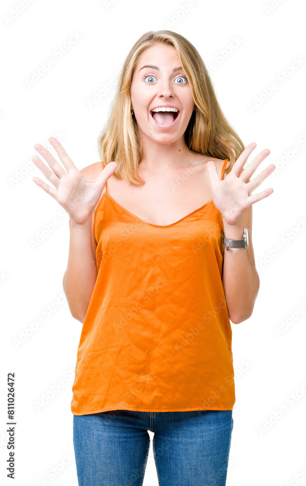 Beautiful young woman wearing orange shirt over isolated background celebrating crazy and amazed for success with arms raised and open eyes screaming excited. Winner concept Beautiful young woman wearing orange shirt over isolated background celebrating crazy and amazed for success with arms raised and open eyes screaming excited. Winner concept