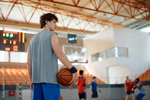 Young basketball player on court with his teammates playing in background. photo