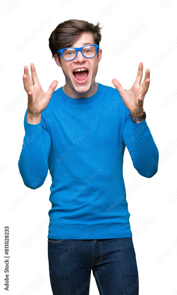 Naklejka premium Young handsome man wearing blue glasses over isolated background celebrating crazy and amazed for success with arms raised and open eyes screaming excited. Winner concept