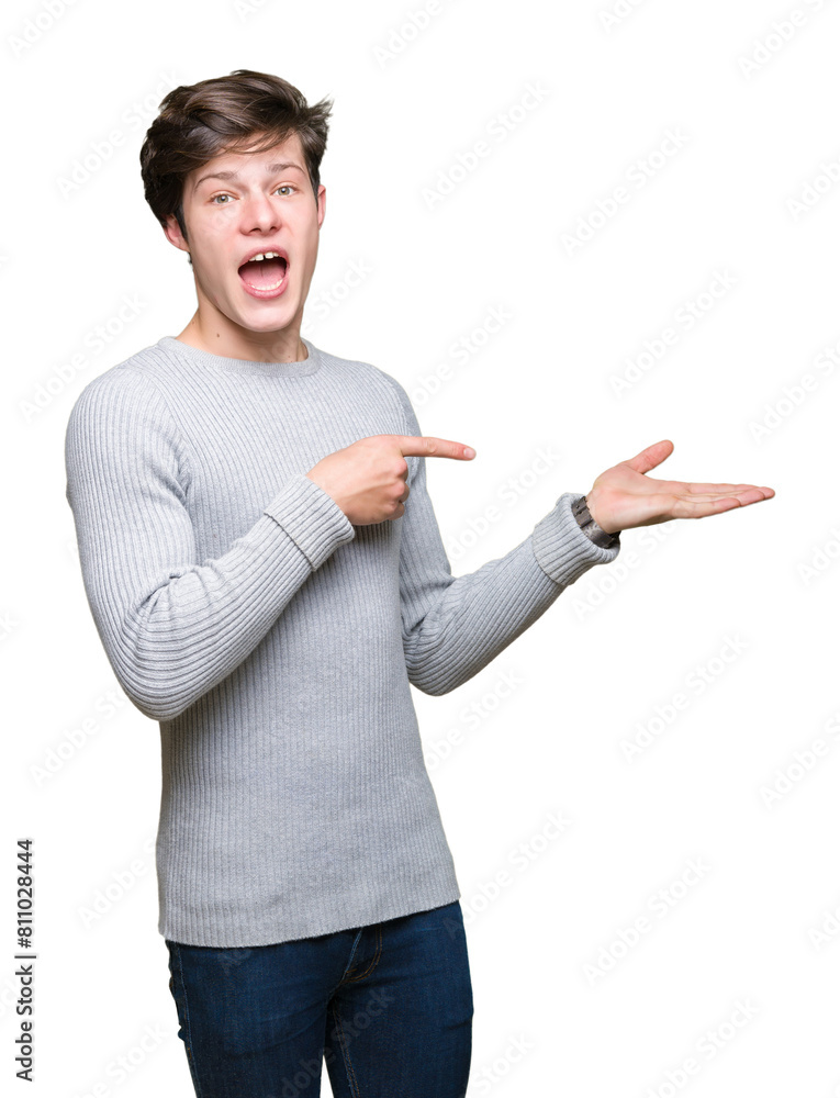 Young handsome man wearing winter sweater over isolated background amazed and smiling to the camera while presenting with hand and pointing with finger. Young handsome man wearing winter sweater over isolated background amazed and smiling to the camera while presenting with hand and pointing with finger.