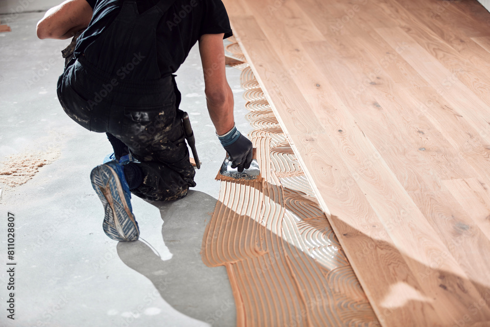 Professional handyman installing laminate flooring in a new apartment.