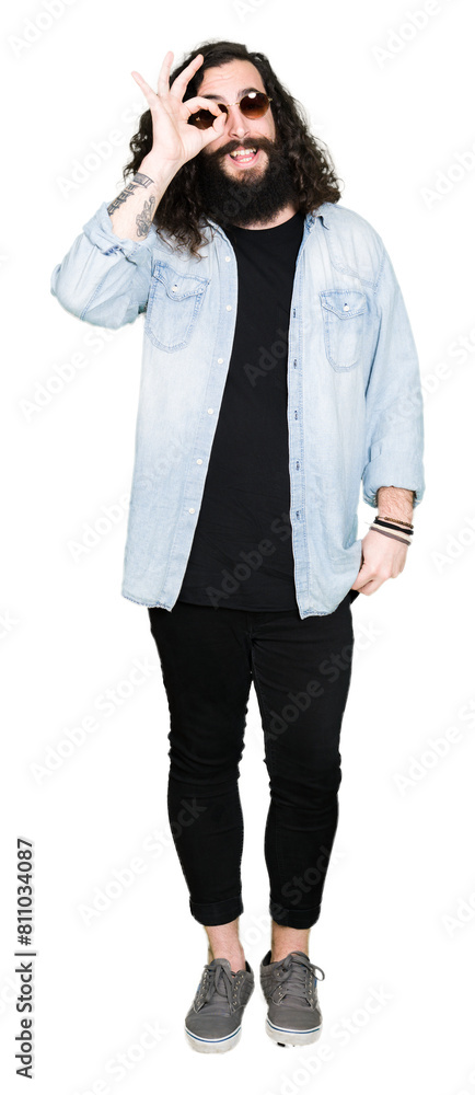 Young hipster man with long hair and beard wearing sunglasses doing ok gesture with hand smiling, eye looking through fingers with happy face. Young hipster man with long hair and beard wearing sunglasses doing ok gesture with hand smiling, eye looking through fingers with happy face.