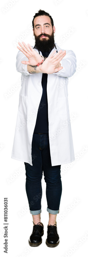 Doctor with long hair wearing medical coat and stethoscope Rejection expression crossing arms and palms doing negative sign, angry face Doctor with long hair wearing medical coat and stethoscope Rejection expression crossing arms and palms doing negative sign, angry face