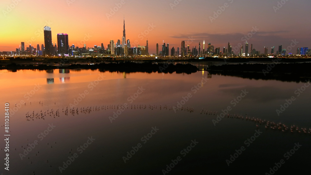Dubai Skyline at sunset with Lake and flamingo drone view 
Drone view from Dubai at sunset, lake and flamingo flock, 2022
