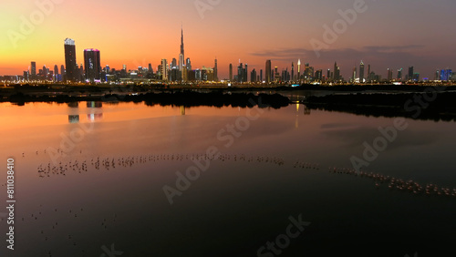 Dubai Skyline at sunset with Lake and flamingo drone view  Drone view from Dubai at sunset  lake and flamingo flock  2022 