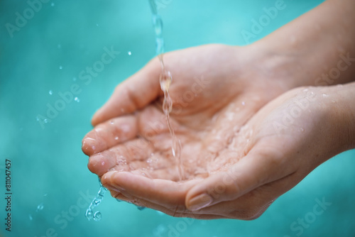 Person, hands and water splash with drops for natural hydration, hygiene or sustainability on a blue background. Closeup of wet consumer with liquid element or fresh mineral for care, hope or nature