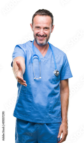 Middle age hoary senior doctor man wearing medical uniform over isolated background smiling friendly offering handshake as greeting and welcoming. Successful business.