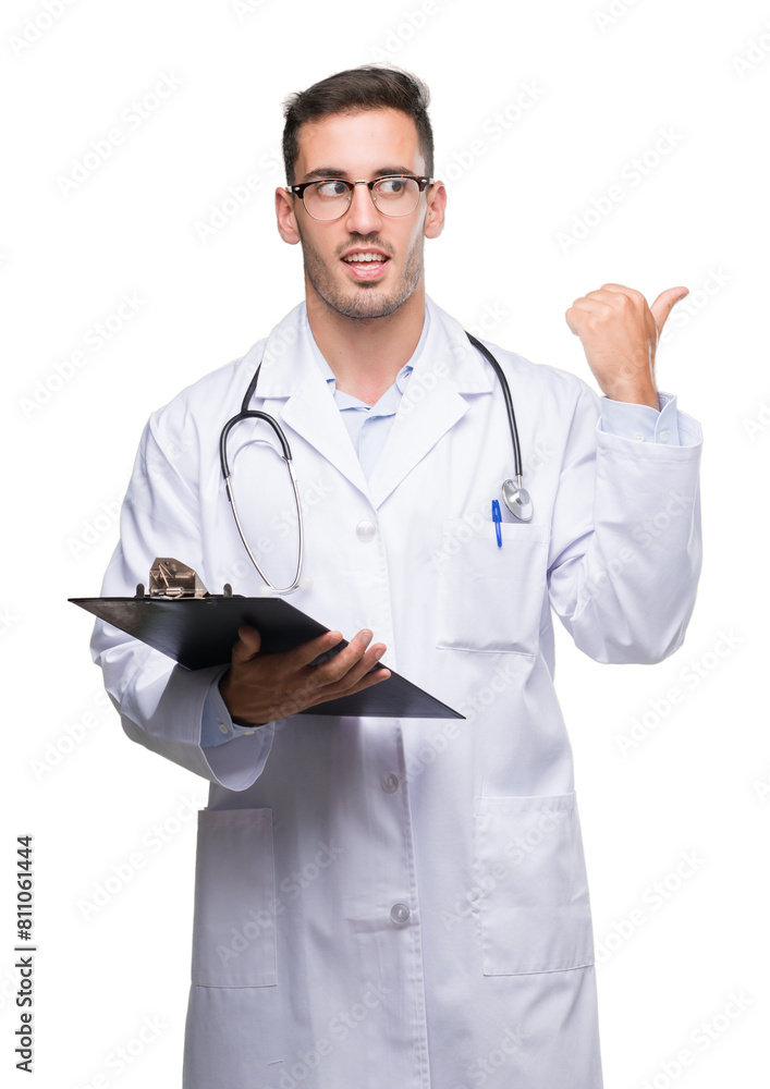 Handsome young doctor man holding a clipboard pointing with hand and finger up with happy face smiling Handsome young doctor man holding a clipboard pointing with hand and finger up with happy face smiling