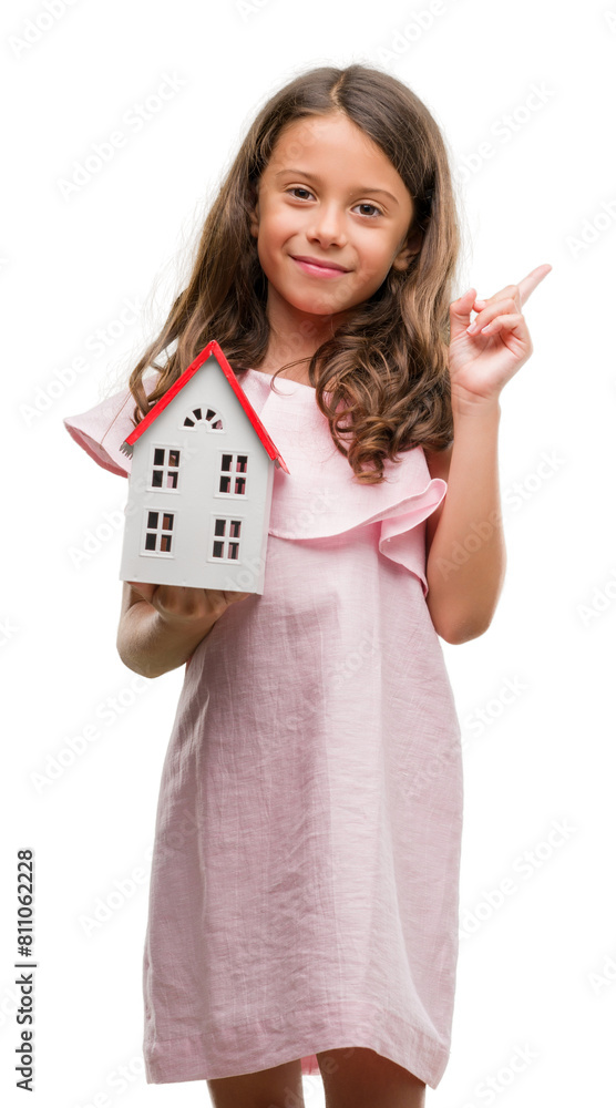 Obraz premium Brunette hispanic girl holding little house very happy pointing with hand and finger to the side