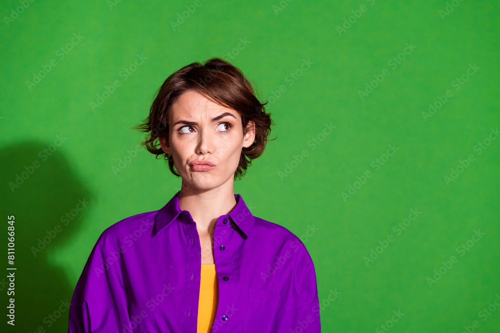 Portrait photo of young distrustful lady pouted lips in purple shirt grimace face thinking looking copyspace isolated on green color background Portrait photo of young distrustful lady pouted lips in purple shirt grimace face thinking looking copyspace isolated on green color background