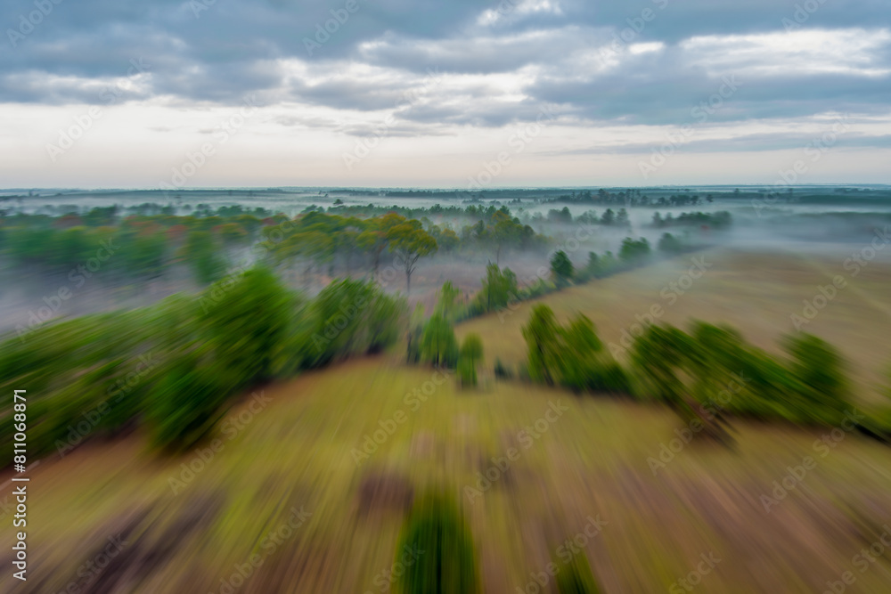 Aerial motion blurred landscape under a dramatic sky with intentional camera movement from a fast moving drone.