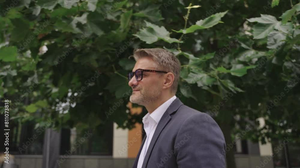 Smiling adult man wearing suit and glasses, walking in the city. Real time concept Smiling adult man wearing suit and glasses, walking in the city. Real time concept