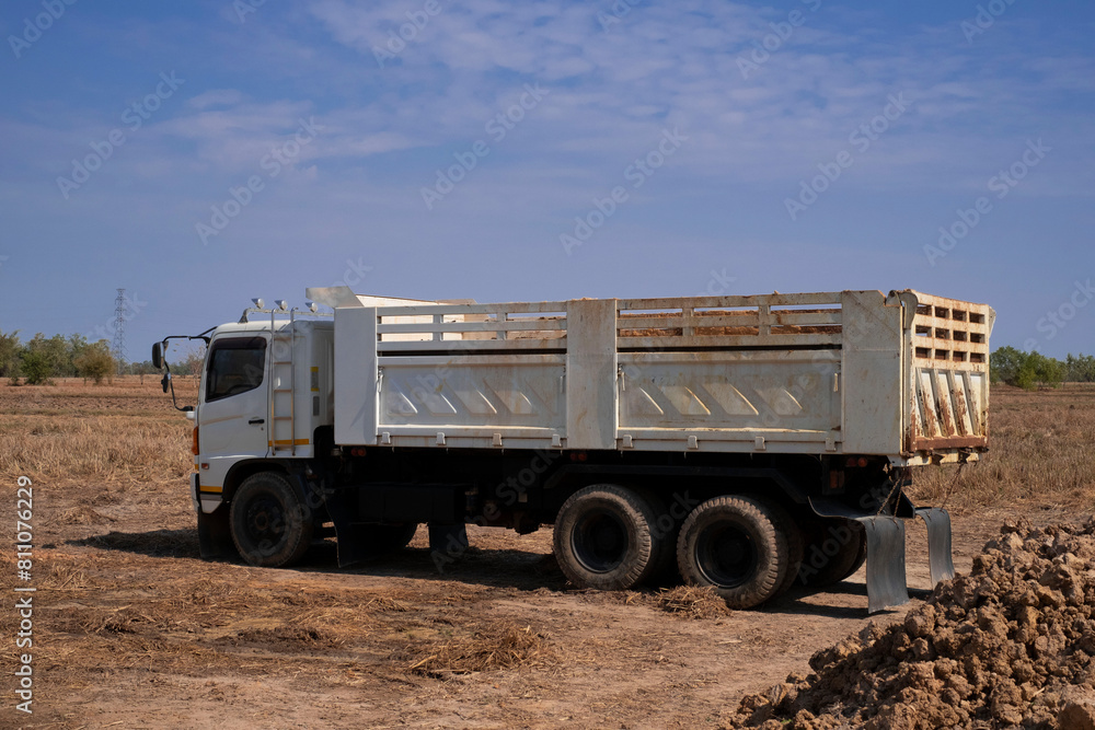 Fototapeta premium Tipper truck dumps its load of soil on a new road. Dump Trucks at a road construction site.