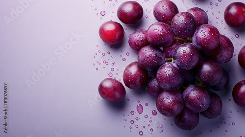  A cluster of grapes resting on a violet background with droplets of water glistening above them