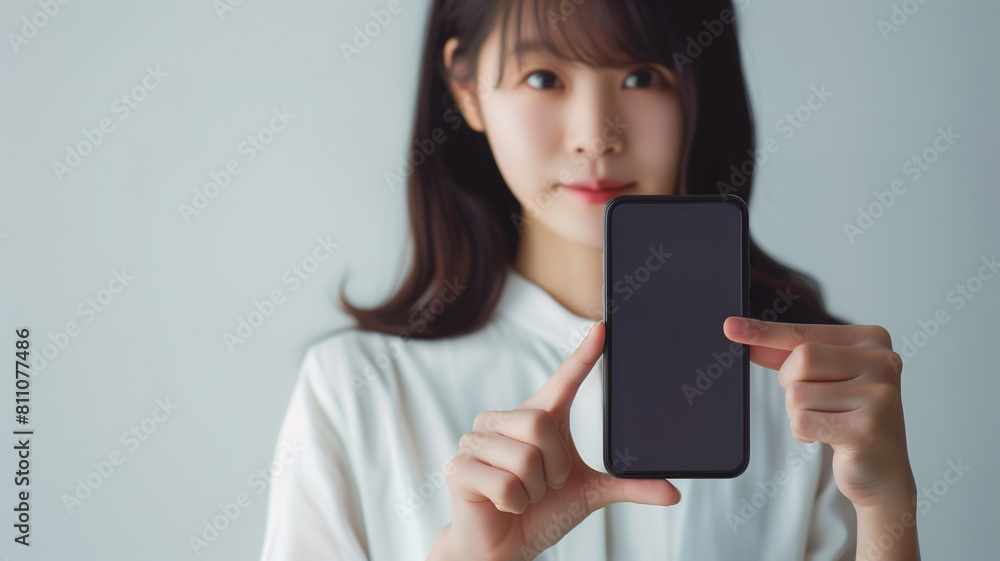Young woman smiling and holding phone..A radiant young Asian woman in a white sweater joyfully presents a smartphone with a blank screen, suitable for display mockups. AI generative.. Young woman smiling and holding phone..A radiant young Asian woman in a white sweater joyfully presents a smartphone with a blank screen, suitable for display mockups. AI generative..