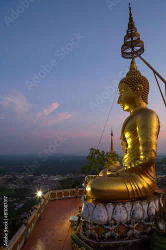Scenic view of the surrounding area and a big golden Buddha statue on top of the mountain at the Tiger Cave Temple  Wat Tham Suea  Sua   in Krabi  Thailand  at dusk.