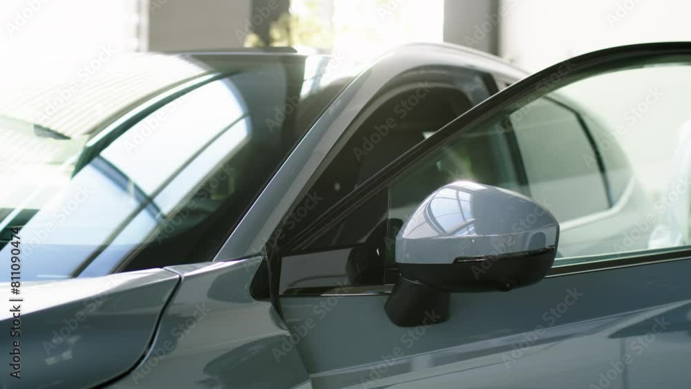 A successful business woman buys an electric car at a car dealership. A young woman enjoys an expensive purchase. Concept of modern automobile technologies, test drive, and insurance. A successful business woman buys an electric car at a car dealership. A young woman enjoys an expensive purchase. Concept of modern automobile technologies, test drive, and insurance.