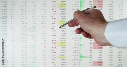 Computer screen displaying Excel spreadsheet with hand holding pen pointing to numbers