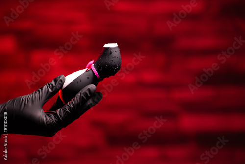 Vibrator in the shape of a penguin. A vacuum-wave clitoral stimulator in the hand of a girl in black latex gloves on a red background. Sex Shop Products, Adult Gifts for Couples, Adult Store