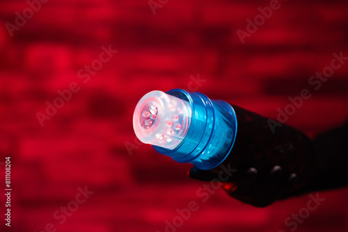 Sex toys for men. Male automatic telescopic masturbator in the hands of a girl in black latex gloves on a red background. Male massager. Sex shop Adult store, toys for two