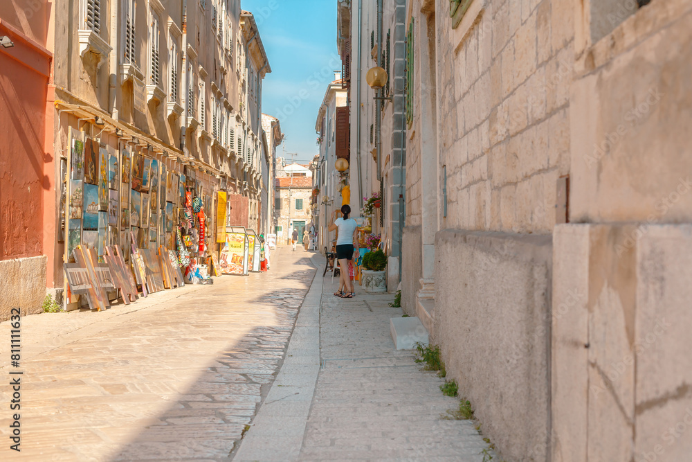 Fototapeta premium Rovinj, Croatia. Picturesque Mediterranean street with outdoor cafes people walking summer sun.