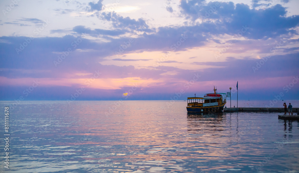 Obraz premium Beautiful sunset over calm sea, with vivid colors and clouds in the sky. Serenity and nature concept