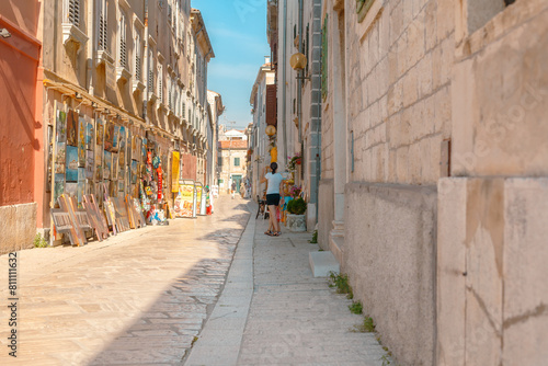 Rovinj  Croatia. Picturesque Mediterranean street with outdoor cafes people walking summer sun.