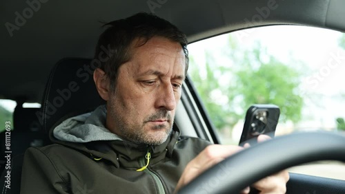 Male driver using smartphone device in car