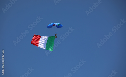 paratrooper with Italian flag on blue sky during National Alpini rally of Italian Military Corp photo