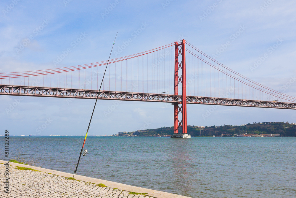 Fototapeta premium Ponte 25 de abril, 25h april bridge with a fishing rod by the river
