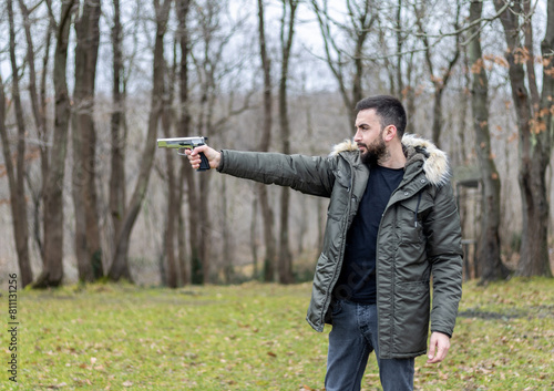 Young man aims and shoots with a gun in the forest