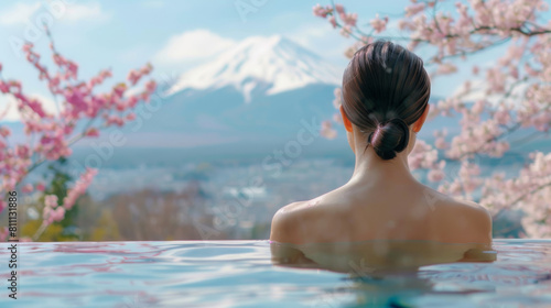 Woman relaxing in an onsen hot springs pool with Mt. Fuji and cherry blossoms