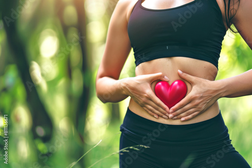 Woman hand's with heart over stomach concept for exercise, diet, fitness, gut health and self love for wellness and training in the summer for healthy workout outside.