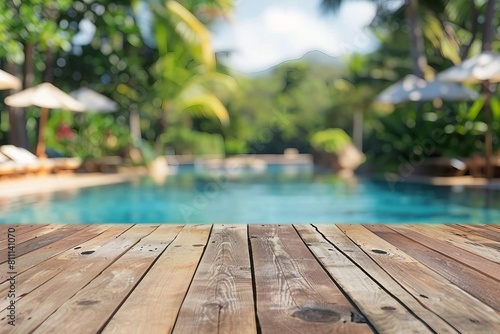 Empty wood table top and blurred swimming pool in tropical resort in summer banner background