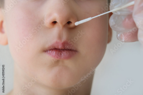 doctor takes cotton bud from child   s nose to analyze the saliva  mucous membrane for DNA tests  COVID-19  boy of 10 years old endures procedure patiently  epidemic concept  coronavirus